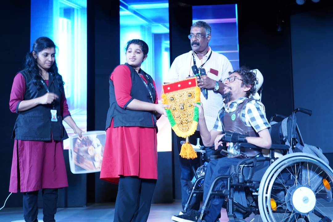 Davey Jose receiving a ceremonial presentation on stage from members of the Kerala event team