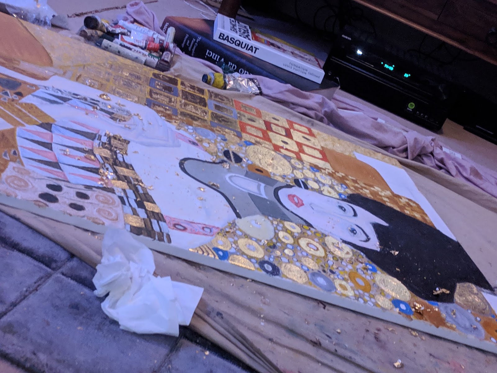 A work-in-progress oil painting after Klimt, with gold leaf, lying on the studio floor beside Basquiat and Da Vinci books
