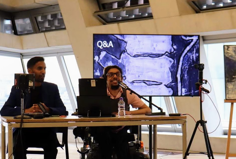 Davey Jose speaking into a microphone during the Q&A, with a blue spinal painting on the screen behind him